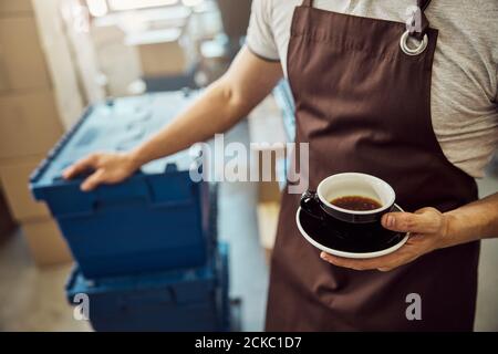Männliche Arbeiter Hand hält schwarze Tasse Kaffee Stockfoto