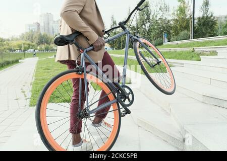 Nahaufnahme eines Mannes, der mit seinem Fahrrad die Treppe hinauf fährt Er wird im Park reiten Stockfoto