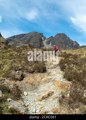 Weibliche Bergwandererin mit Rucksack aufsteigender Bergweg an den unteren Hängen von Blaven in den Black Cuillin Mountains, Isle of Skye, Schottland, Großbritannien Stockfoto