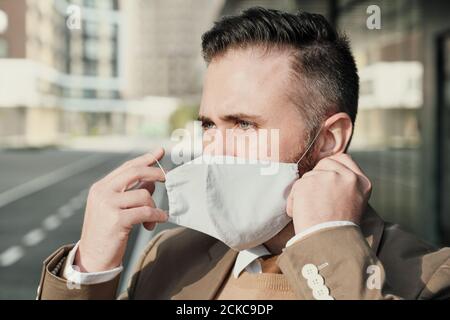 Reifer Mann trägt Schutzmaske vor dem Betreten des Büros Gebäude Stockfoto