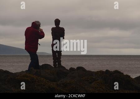 Anthony Gormleys Skulptur, GRIP und ein Mann 60+, der auf Felsen in Saddell Bay, Kintyre, Argyll, Schottland steht und zusammen über den Kilbrannan Sound blickt Stockfoto