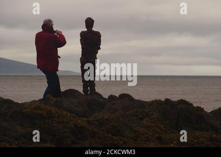 Anthony Gormleys Skulptur, GRIP und ein Mann 60+, der auf Felsen in Saddell Bay, Kintyre, Argyll, Schottland steht und zusammen über den Kilbrannan Sound blickt Stockfoto