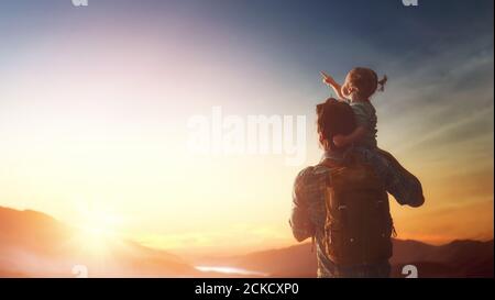 Glückliche Familie bei Sonnenuntergang. Vater und Tochter haben Spaß und genießen Reise. Baby sitzt auf den Schultern seines Vaters. Stockfoto