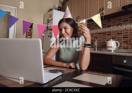 Asiatische Frau virtuelle Happy Hour Treffen Geburtstagsfeier mit Kuchen online, zusammen mit ihrem Freund in der Videokonferenz. Mädchen feiert Geburtstag online Stockfoto