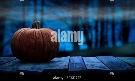 Eine gruselige halloween Kürbis leere Vorlage auf einer Holzbank mit einem nebligen Wald Nacht Hintergrund mit Platz für Produktplatzierung. Stockfoto