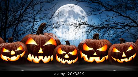 Fünf gruselige halloween Kürbisse in Folge, Jack O Laterne, mit bösem Gesicht und Augen auf einer Holzbank, Tisch mit einem nebligen Nachtwald und Vollmond zurück Stockfoto