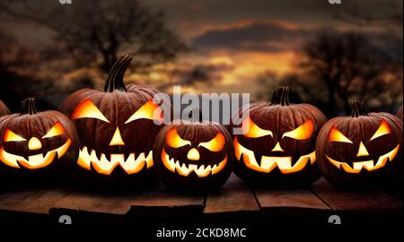 Fünf gruselige halloween-Kürbis, Jack O Laterne, mit einem bösen Gesicht und Augen auf einer Holzbank, Tisch mit Sonnenuntergang, Nachthintergrund. Stockfoto