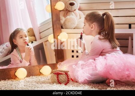 Glückliches Mädchen verkleidet sich zu Hause. Lustige schöne Kind hat Spaß mit Lippenstift im Kinderzimmer. Stockfoto