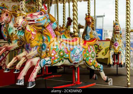 Ein traditionelles Pferderennen-Karussell am Brighton Palace Pier in East Sussex, England mit Blick auf Brighton im Hintergrund Stockfoto