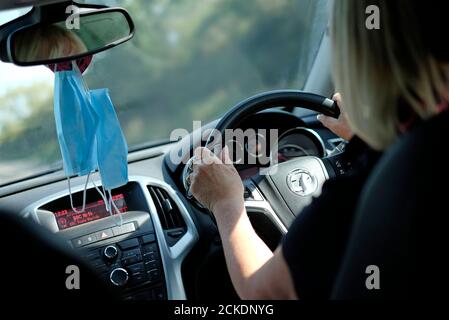 Weibliche Fahrer Auto mit Gesichtsmasken hängen von Rückspiegel, norfolk, england Stockfoto