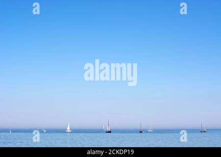 Yachten und Segelboote in der Ferne auf ruhigem Wasser, klarem blauen Himmel. Meereslandschaft. Mit Kopierbereich Stockfoto