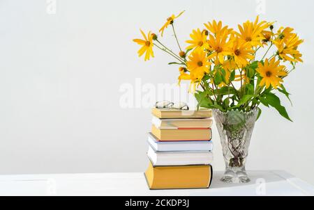 Zurück zur Schule Konzept. Orange Blumen in einer Vase auf dem Tisch des Lehrers. Stapel von Schulbüchern und Brille des Lehrers. Tag des Lehrers Selebration. Copy Space. Stockfoto