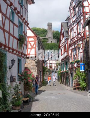 Touristen gehen in der Nähe Fachwerkhäuser und Burgruine in Schönes Dorf Monreal in der deutschen eifel Stockfoto