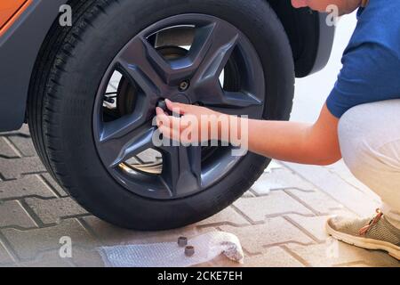 Сar Fahrer mit verschiedenen Reparaturwerkzeugen für die Installation von Kappen auf Schrauben auf Autorädern. Konzept der Fahrzeugwartung. Stockfoto