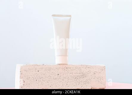 Weiße Tube kosmetischen Produkts ohne Marke auf einem Sockel oder Podium. Hautpflege Lotion oder Creme auf einem trendigen Display. Gesicht Schönheit Mockup. Tmplate mit Platz für Text kopieren. Stockfoto