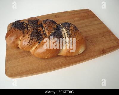 Bun Pigtail mit Mohn Nahaufnahme auf einem Holzbrett. Stockfoto