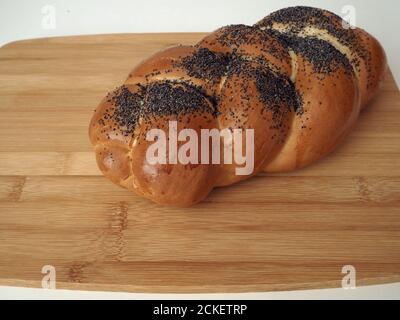 Bun Pigtail mit Mohn Nahaufnahme auf einem Holzbrett. Stockfoto