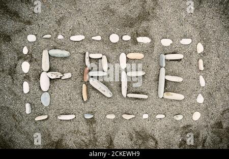 Inschrift von FREIEN Kieselsteinen am Sandstrand Stockfoto