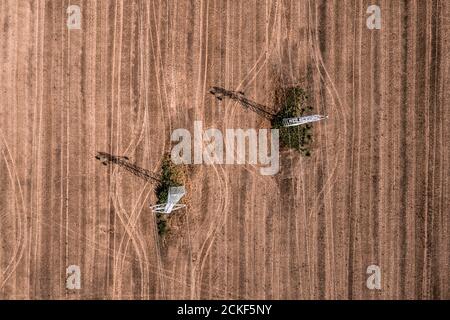 Luftaufnahme von Strommasten in landwirtschaftlichen Feldern, die Schatten auf Feldfrüchten werfen, Draufsicht Drohnenfotografie Stockfoto