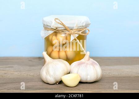 Marinierter Knoblauch im geschlossenen Glas und frisch auf Holz Tabelle gesunde fermentierte Lebensmittel hausgemachte Gurken Stockfoto