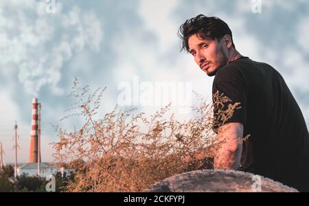 Porträt eines jungen Mannes in einem schwarzen Outfit in Eine Industriezone Stockfoto