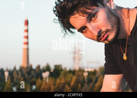 Nahaufnahme eines jungen Mannes in einem schwarzen Outfit In einem Industriegebiet Stockfoto