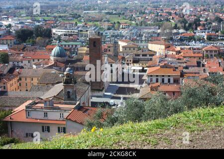 Die roten Dächer der bewohnten Häuser, die Kirche und der Glockenturm der kathedrale von pietrasanta vom Grün eines Hügels an der Spitze aus gesehen Stockfoto