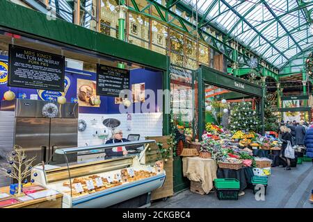 Ein Markttrader, der hinter dem Tresen an einem Stall steht Verkauf von Kuchen und Quiche im Borough Market, Southwark, London Stockfoto