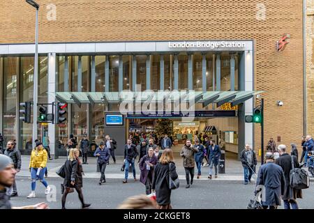 Pendler, die die Straße an einer kontrollierten Kreuzung außerhalb der Tooley Street Eingang in London Bridge Station, Southwark, London überqueren Stockfoto