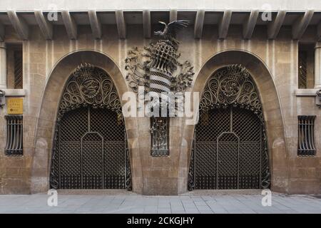 Haupttor des Palau Güell, entworfen vom katalanischen modernistischen Architekten Antoni Gaudí in Barcelona, Katalonien, Spanien. Das Herrenhaus im Auftrag des katalanischen Industriemagnaten Eusebi Güell wurde zwischen 1886 und 1890 erbaut. Zwischen zwei Hufeisenbögen ist das geschmiedete Wappen Kataloniens abgebildet. Die geschmiedeten Eisenmonogramme E und G werden an den Besitzer des Herrenhauses verwiesen. Stockfoto