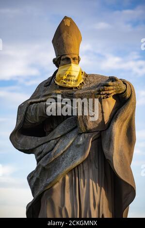 Statue des Heiligen Bruno auf der Alten Mainbrücke von Würzburg, Deutschland mit einer Gesichtsmask mit den Worten "Vermeiden Sie Corona" Stockfoto