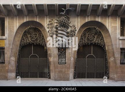 Haupttor des Palau Güell, entworfen vom katalanischen modernistischen Architekten Antoni Gaudí in Barcelona, Katalonien, Spanien. Das Herrenhaus im Auftrag des katalanischen Industriemagnaten Eusebi Güell wurde zwischen 1886 und 1890 erbaut. Zwischen zwei Hufeisenbögen ist das geschmiedete Wappen Kataloniens abgebildet. Die geschmiedeten Eisenmonogramme E und G werden an den Besitzer des Herrenhauses verwiesen. Stockfoto