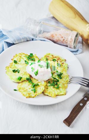 Gemüsezucchini-Pfannkuchen mit pochiertem Ei auf weißem Teller Stockfoto