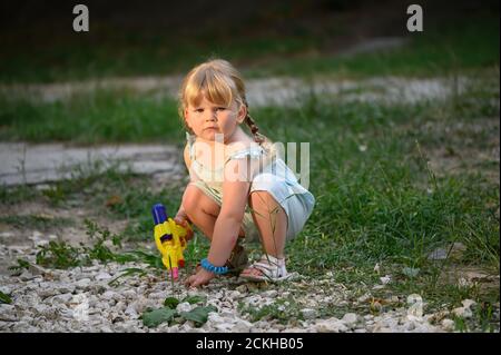 Kleines blondes Mädchen mit einer Wasserpistole Stockfoto