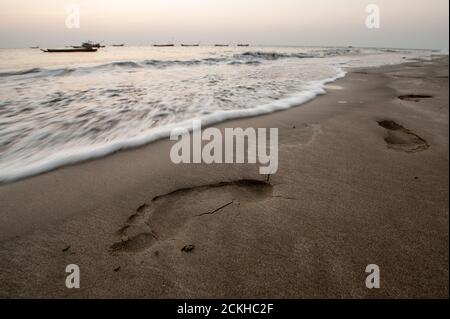 Fußabdrücke am Strand mit Fischerbooten am Horizont In der Nähe von Ngwe Saung in Myanmar Stockfoto