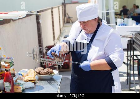 Weißrussland, Bezirk Gomel am 17. Juli 2020. Die Straßen der Stadt. Die Köchin auf der Straße bereitet einen Hamburger zu. Stockfoto