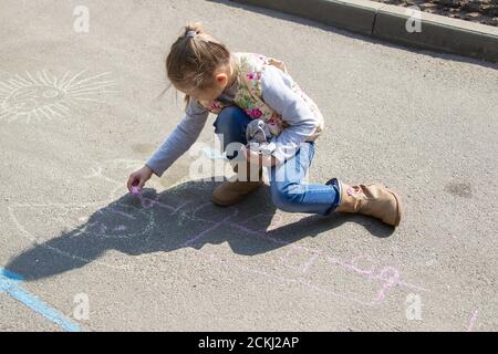 Weißrussland, Gomel, 30. Mai 2019. Ein Tag der offenen Tür in einem Kindergarten. Ein Mädchen aus der Vorschule zieht mit Kreide auf den Asphalt. Stockfoto