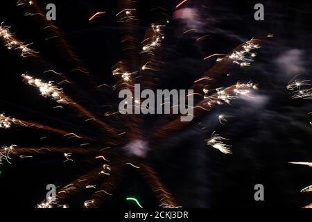 Lichtflecken von Feuerwerkskörpern in goldener Farbe auf einer langen Belichtung auf schwarzem Hintergrund. Festlicher Hintergrund. Stockfoto