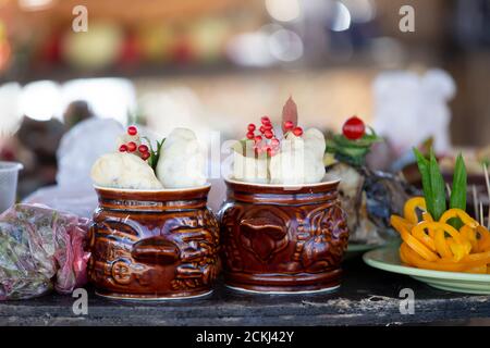 Zwei Tonerbsen mit rustikalem Essen.auf dem Tisch stehen Töpfe mit Kartoffeln. Stockfoto