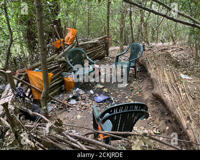 Eine Droge, Kleber schnüffeln und Alkohol Höhle in Wald bei Godalming in Surrey, England. Plastiktüten von ausrangierten Bier und Klebestiften streut das Land Stockfoto