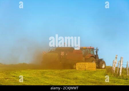 Traktor arbeitet während der Ernte auf der Cezallier-Hochebene im regionalen Naturpark der Vulkane der Auvergne, Puy de Dome, Auvergne-Rhone-Alpes, Frankreich Stockfoto