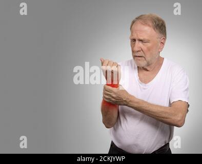 Leiden an Schmerzen und Rheuma. Nahaufnahme Ältere, ältere alte Mann, der miserabel in großen qualvollen Handschmerzen schmerzhafte Handgelenk in rot iso gefärbt Stockfoto