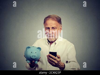 Ein besetzter Mann, der sein Handy mit dem Sparschwein betrat Stockfoto