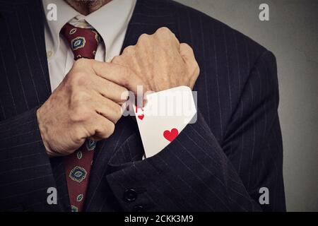 Nahaufnahme beschnittenes Bild Senior Mann Hand ziehen aus einem versteckten ace aus der Hülse isoliert auf grauem Wandhintergrund Stockfoto