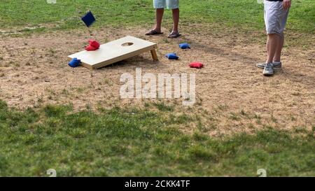 Sommertag in einem öffentlichen Park vier Leute spielen die Cotnhole Spiel Stockfoto