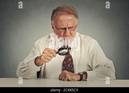 Portrait Senior mürrisch Geschäftsmann Blick durch eine Lupe Stockfoto