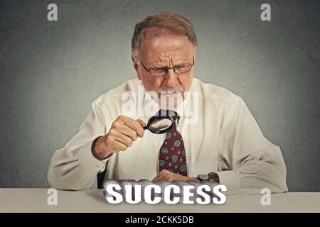 Skeptischer Blick auf den Erfolg. Senior Business man reifen Chef in Anzug Blick durch Lupe Analyse Erfolgszeichen Stockfoto