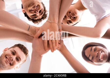 Ansicht von unten multikulturelle Freiwillige, die die Kamera betrachten, während sie halten Hände Stockfoto