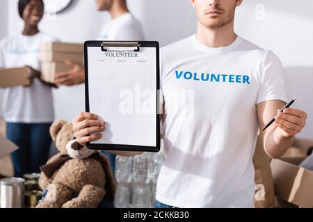 Selektiver Fokus der Freiwilligen hält Zwischenablage und Stift in der Nächstenliebe Zentrieren Stockfoto