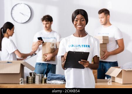 Selektiver Fokus der afroamerikanischen Freiwilligen hält Zwischenablage und suchen Bei der Kamera im Charity Center Stockfoto